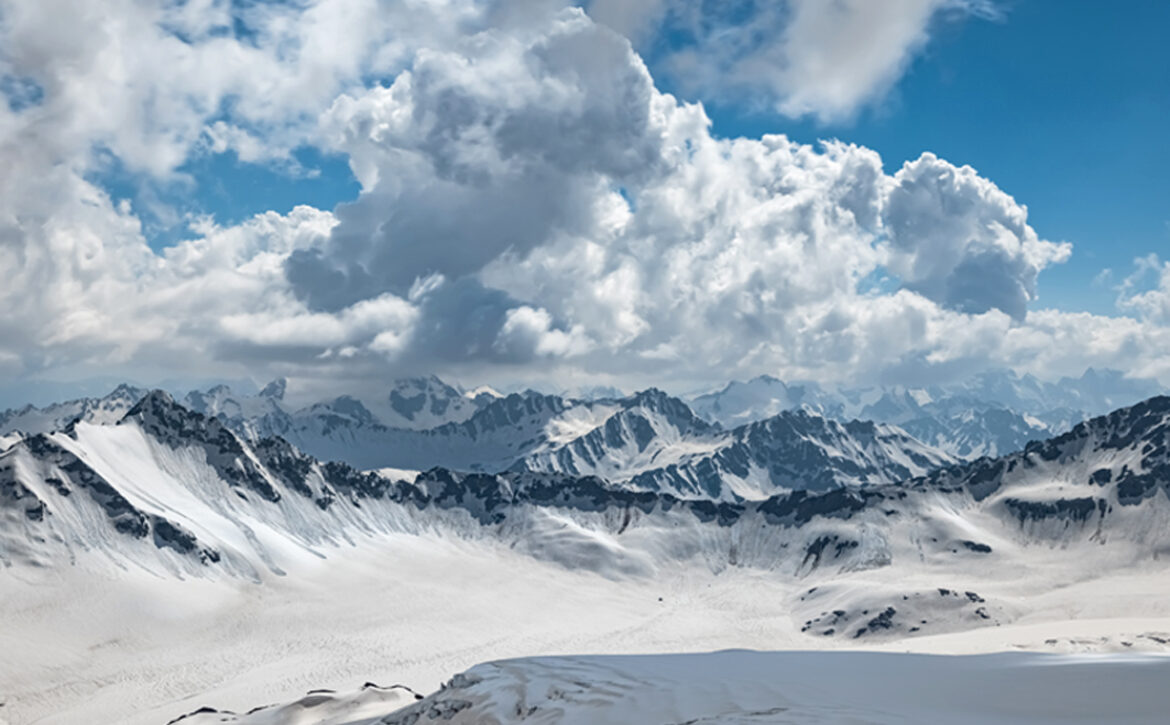 Mountain clouds over beautiful snow-capped peaks of mountains an